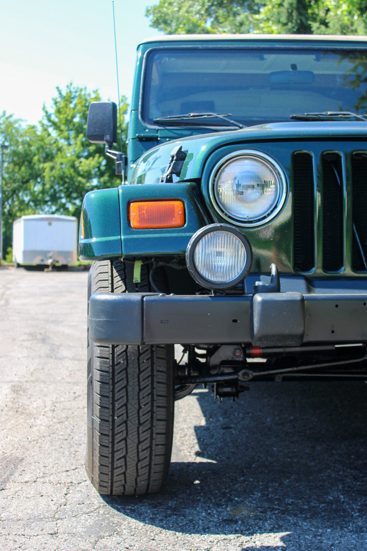 Front of a green jeep in a gravel parking lot